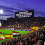 A football player standing on the pitch while the stadium screen shows a warning against Islamophobic and xenophobic chants during the Spain vs Egypt match.